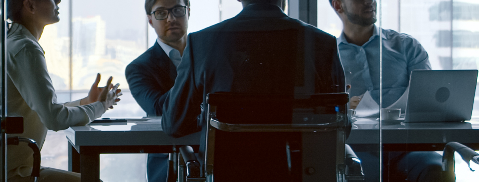 Executives meeting around a conference table in a glass-walled conference table